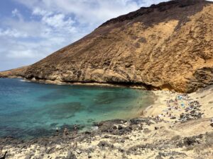 Cala de agua transparente con montaña volcánica en La Graciosa